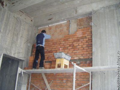 ici un ouvrier continue le mur de brian et nicolas